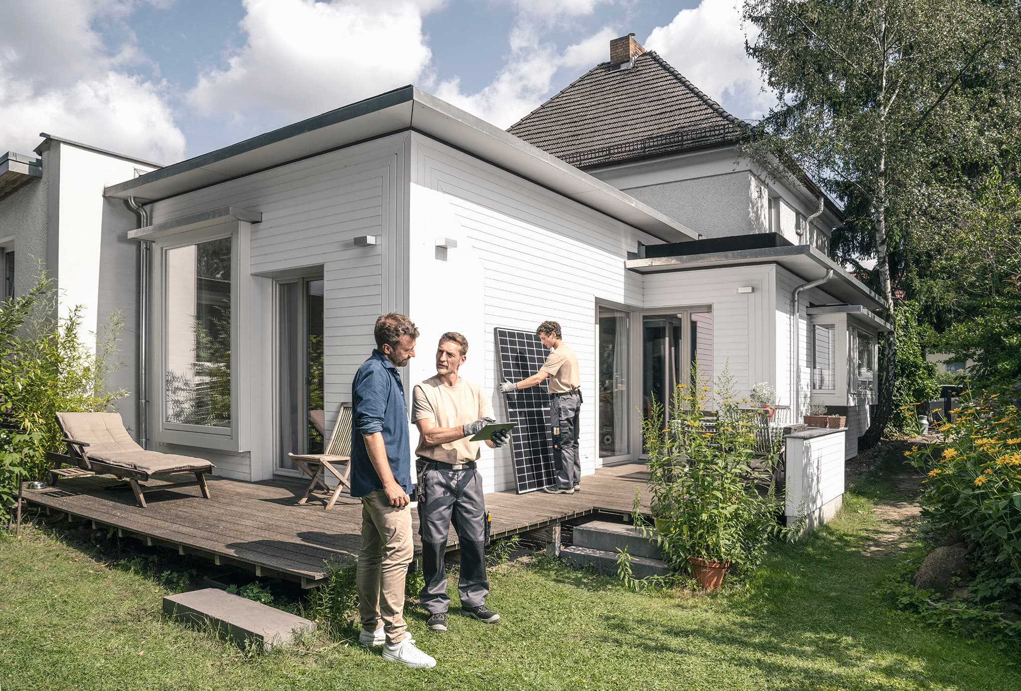 Installationsteam mit Kunden im Garten - mit zolar Installateuren zur PV-Anlage