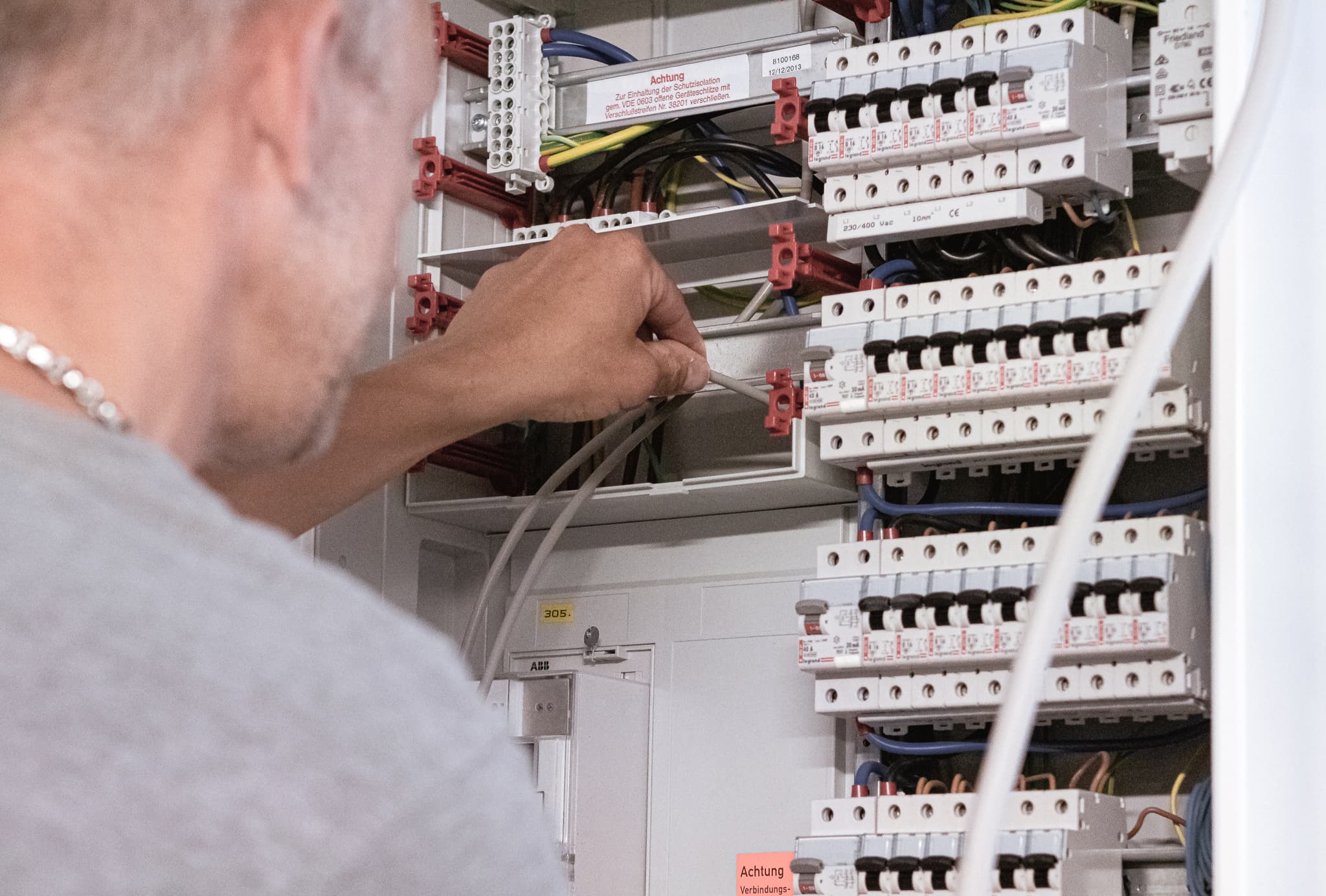Elektroinstallateur vor dem Zählerschrank – Einbau eines Stromzählers