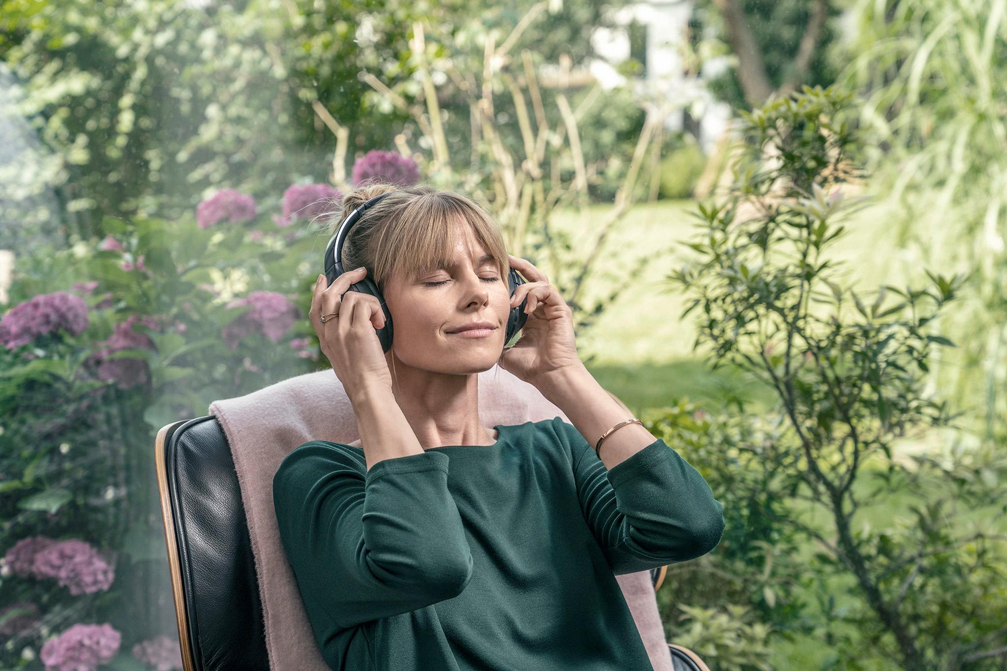 Frau hört im Garten Musik – Mit privater Unabhängigkeit zur Energiewende