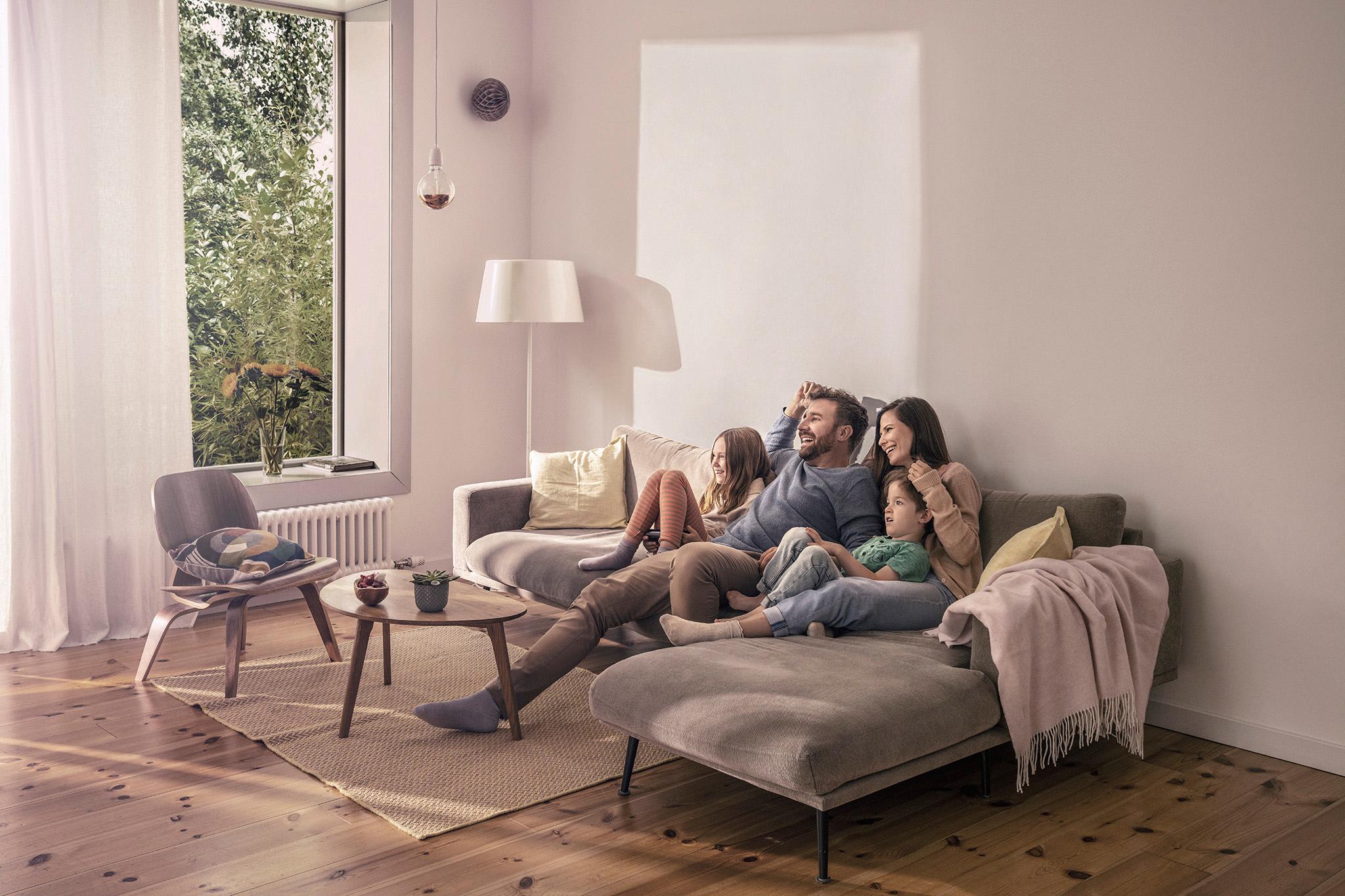 Vierköpfige Familie sitzt auf dem Sofa – PV und Stromspeicher kaufen bei zolar