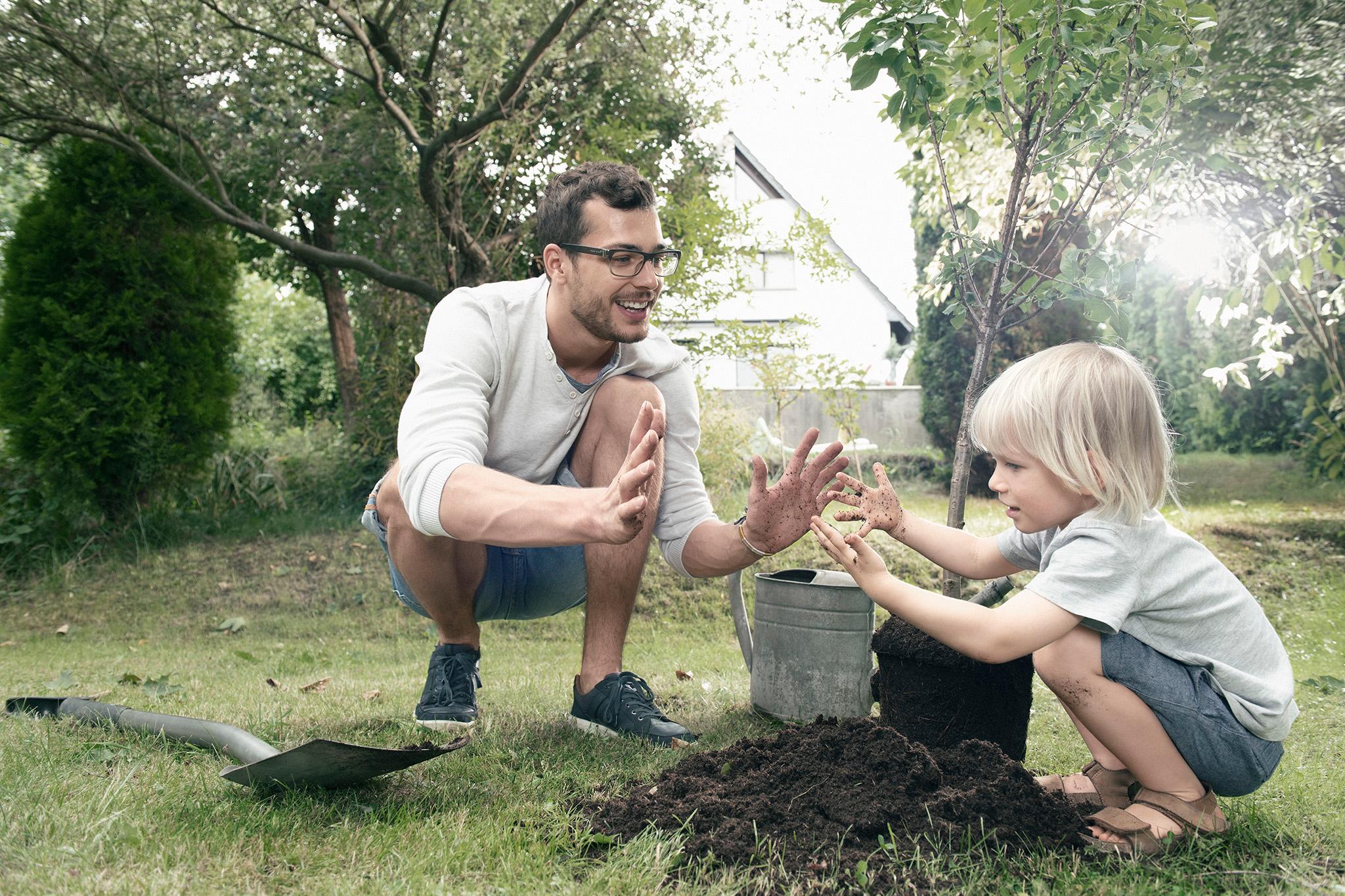 Mann und Kind pflanzen Baum im Garten - Ökostrom sinnvoll?