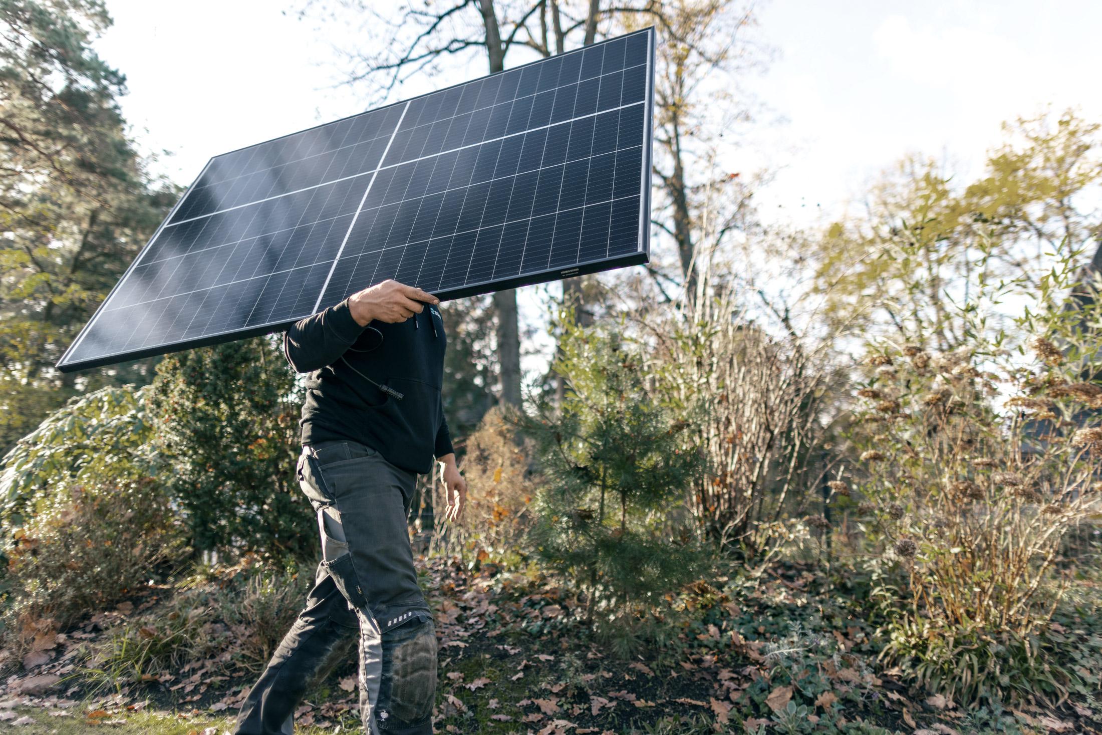 Installateur mit Solarmodul auf dem Arm – Wie viel Strom produziert eine Mini PV-Anlage?