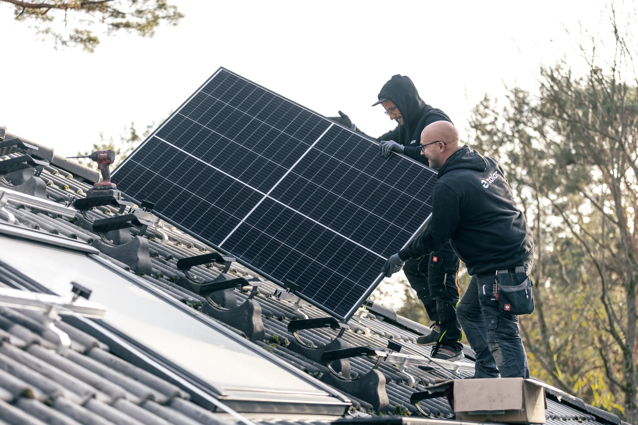 zolar Monteure mit Solarmodul auf dem Dach – Kleinunternehmerregelung PV
