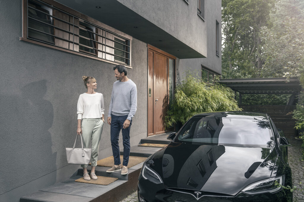 Paar mit E-Auto vor einem Haus – Kosten für eine intelligente Wallbox